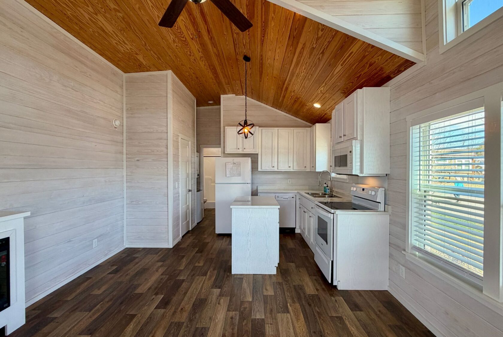 Modern kitchen at 119 Breezy Meadow Lane with white cabinets, wood ceiling, island, and wood-style flooring.