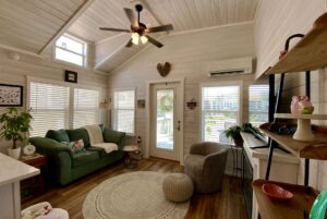 Cozy living room with vaulted ceiling, green sofa, and sunlit windows—perfect for strolling Easy Lane in comfort.