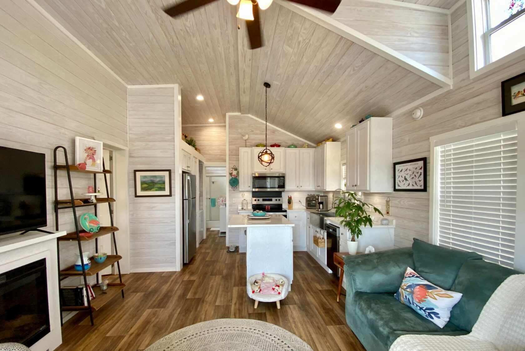 Bright, modern living room and kitchen with wood accents, teal sofa, and a Strolling Easy Lane vibe.