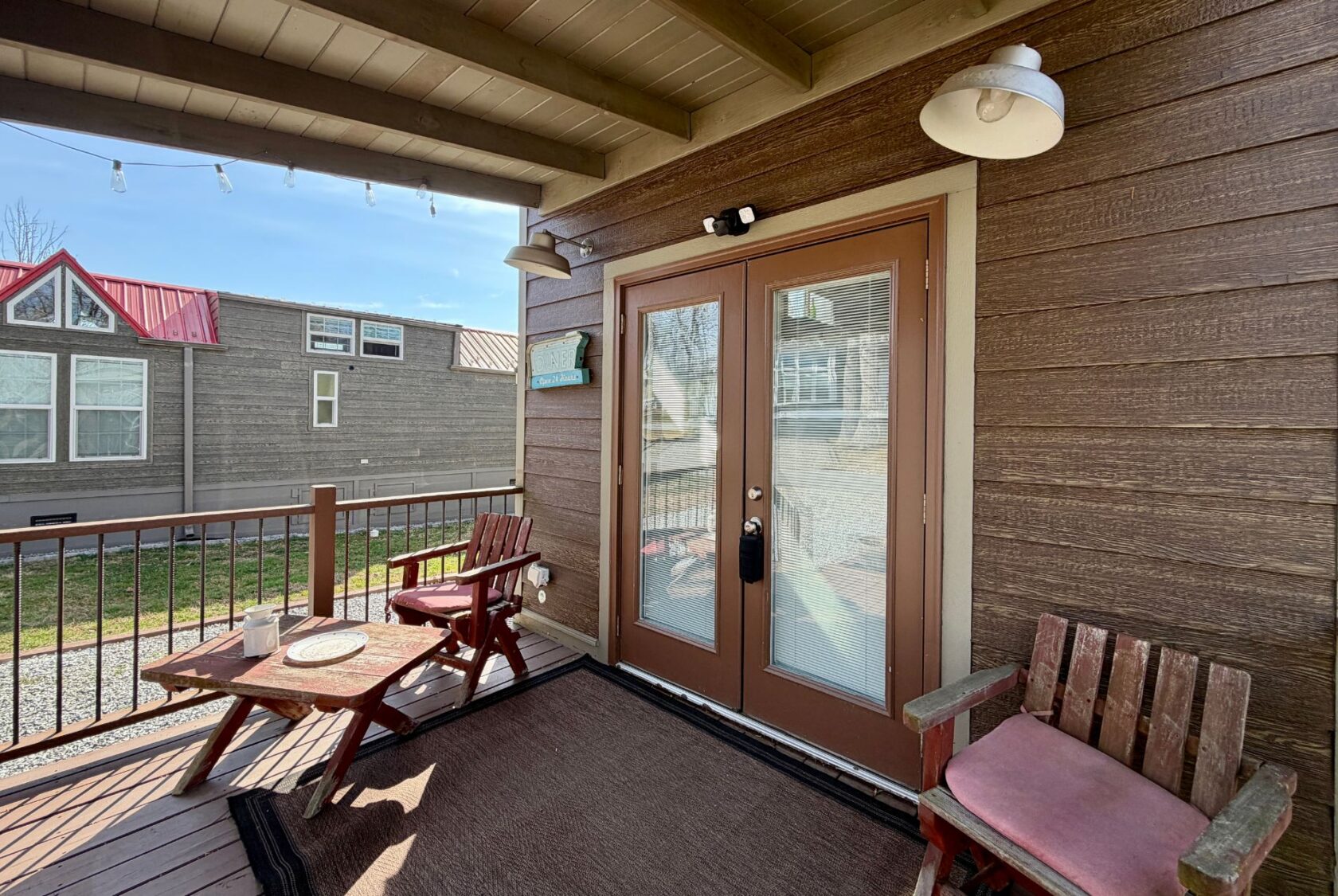 Cozy porch at 31 Rest Awhile Lane with two wooden chairs, a table, and double doors on a sunny day.