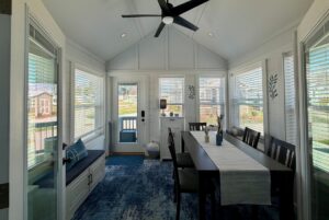 Bright sunroom at 67 Mount Meadow Lane with large windows, dining table, blue rug, and scenic outdoor view.