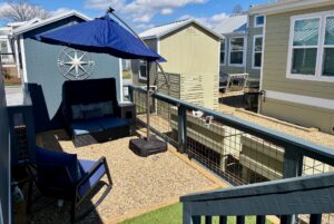 Cozy outdoor patio with seating, umbrella, and gravel ground on Mount Meadow Lane between modern tiny homes.