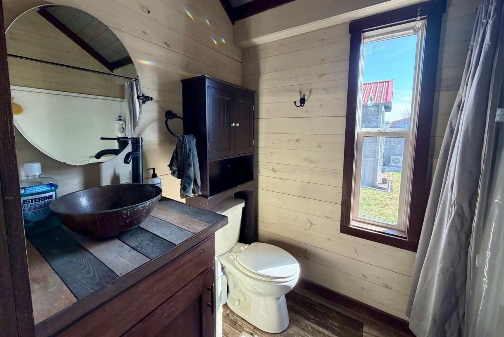 Rustic bathroom at 31 Rest Awhile Lane with wood accents, vessel sink, and cabinet; natural light shining in.