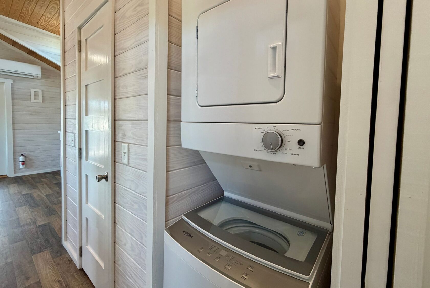 Stacked washer and dryer in a cozy laundry area at 119 Breezy Meadow Lane with wood-paneled walls and flooring.