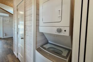 Stacked washer and dryer in a cozy laundry area at 119 Breezy Meadow Lane with wood-paneled walls and flooring.