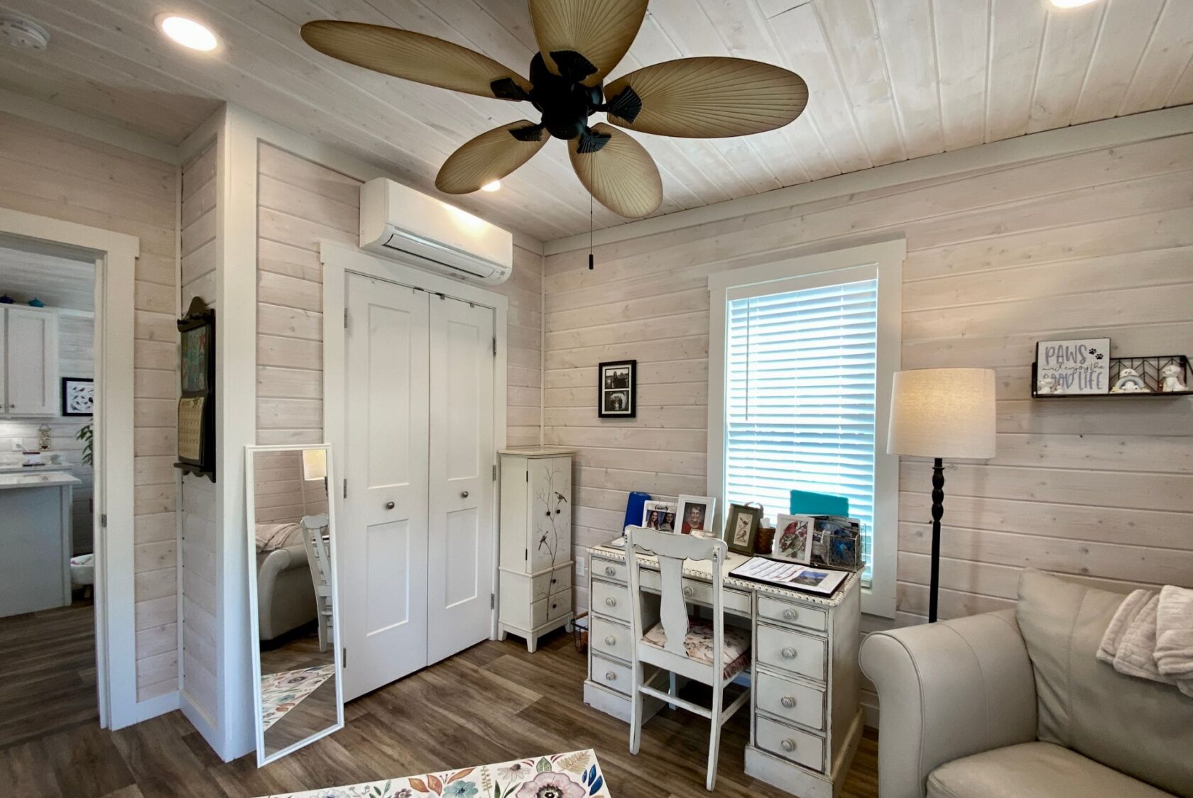 Cozy cottage room with a white desk, mirror, and palm leaf ceiling fan—perfect for strolling down Easy Lane.