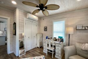 Cozy cottage room with a white desk, mirror, and palm leaf ceiling fan—perfect for strolling down Easy Lane.