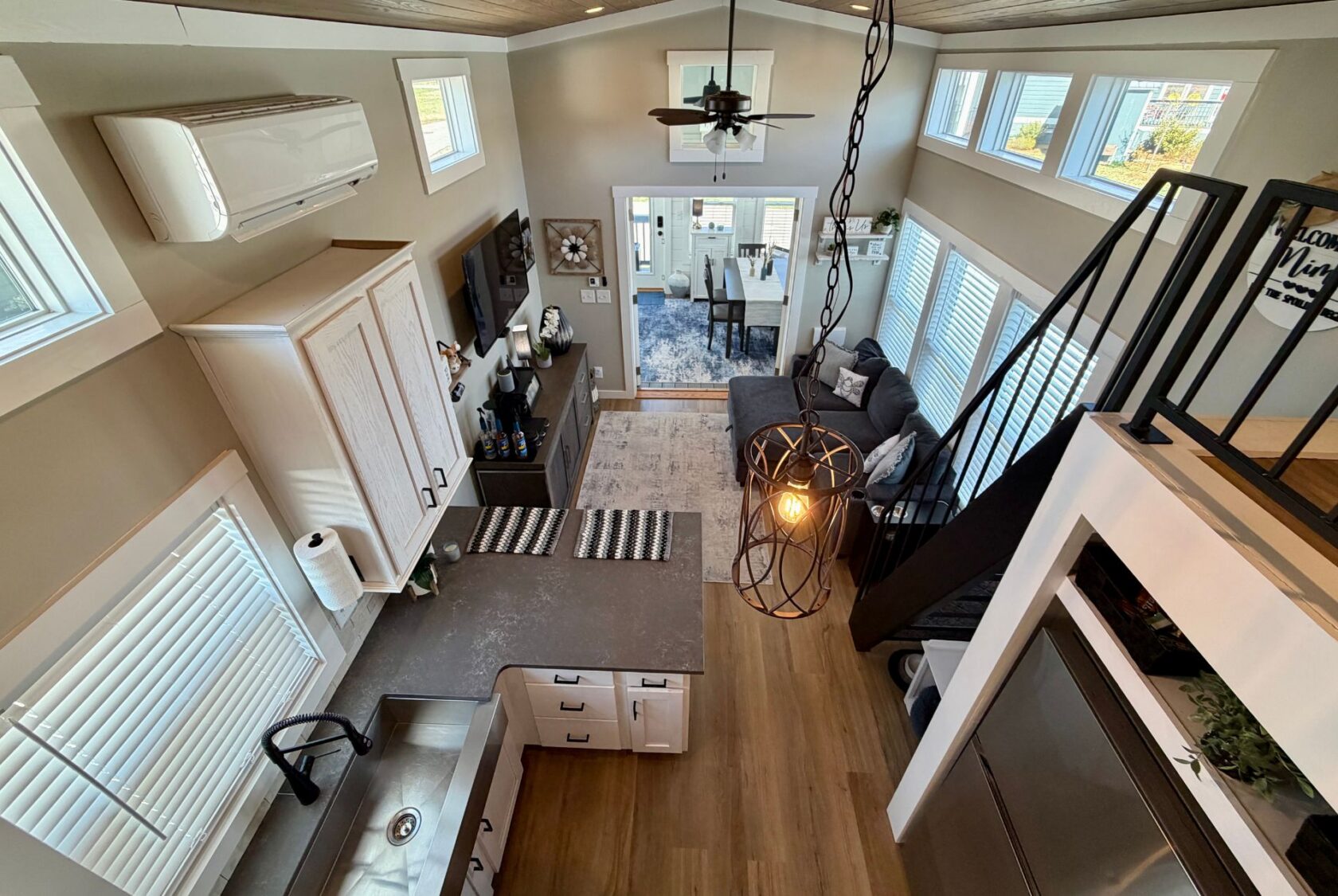 A modern Mount Meadow Lane tiny house interior with a kitchen, living area, loft, and large windows letting in natural light.