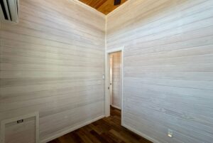 Empty room with white wood panel walls, wooden floor, and a door—perfect for Breezy Meadow Lane living.