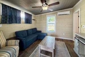 Cozy living room with blue sofa, striped armchair, and coffee table in a Highland Hill Lane wood-paneled space.