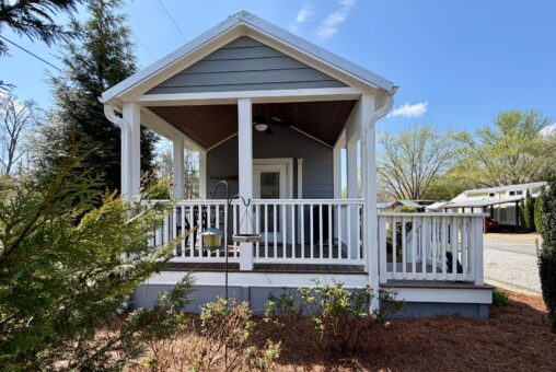 Charming gray house with a porch and garden at 47 Drifting Brook Lane—perfect real estate opportunity.