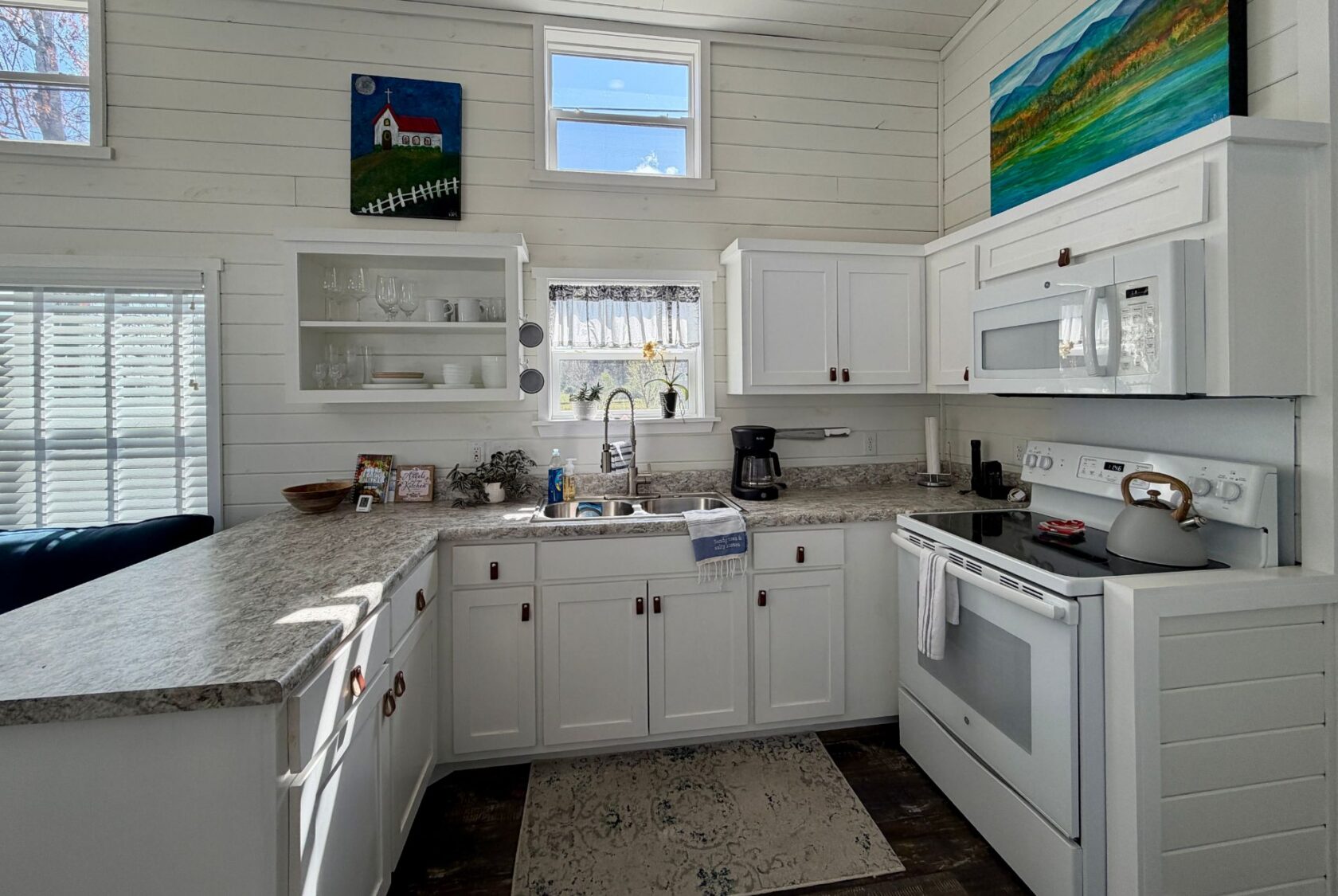 Bright, cozy kitchen at 47 Drifting Brook with white cabinets, sunlight, and colorful paintings—perfect for real estate photos.