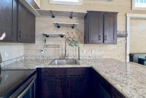 Modern kitchen at 53 Highland Hill Lane with dark cabinets, granite counters, sink, mugs, and light wood paneled walls.