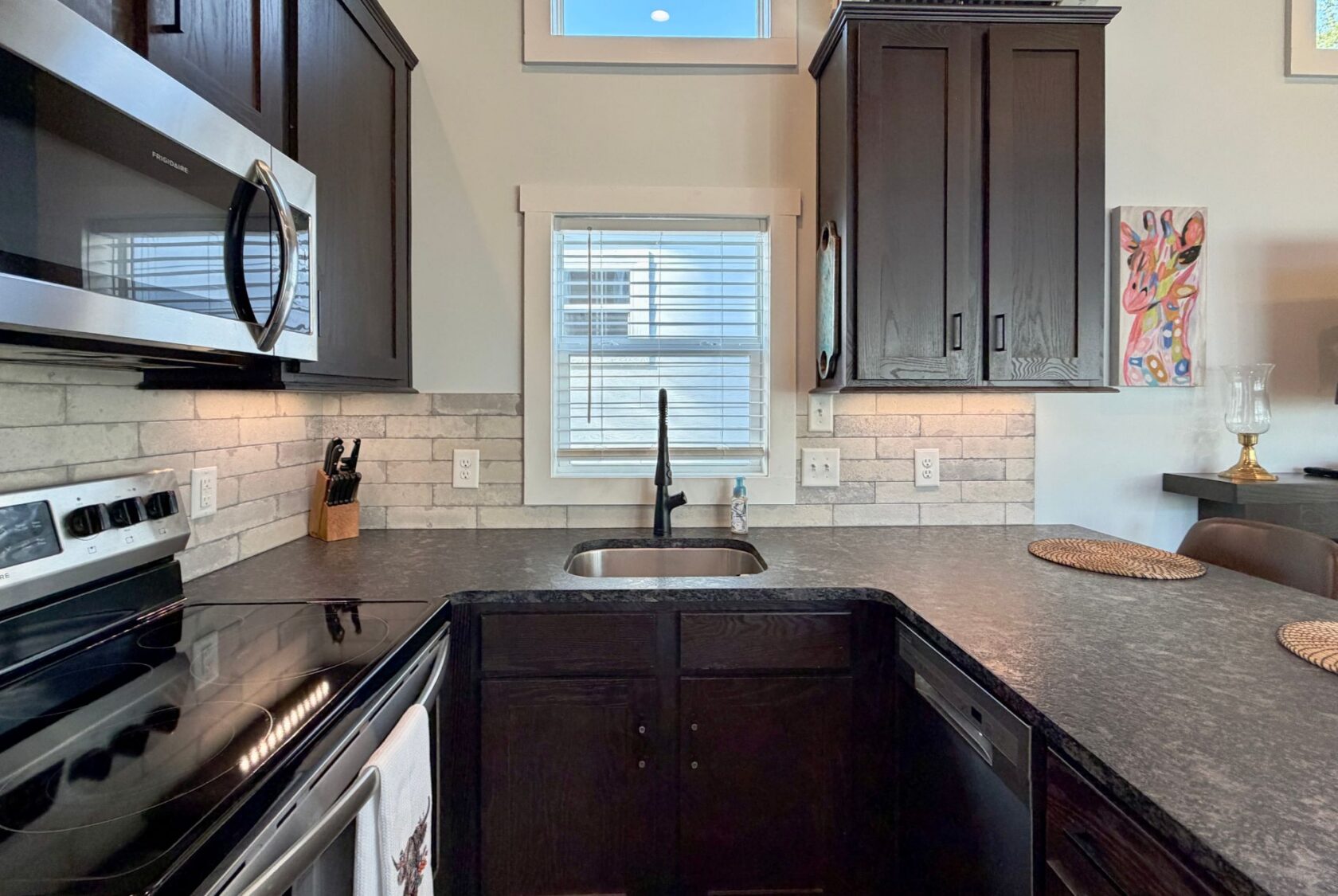 Modern kitchen at 106 Meandering Lane with dark cabinets, stainless steel appliances, and a sink under the window.