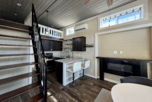 Modern tiny house interior at 53 Highland Hill Lane with loft, dark wood kitchen, granite island, and spiral staircase.