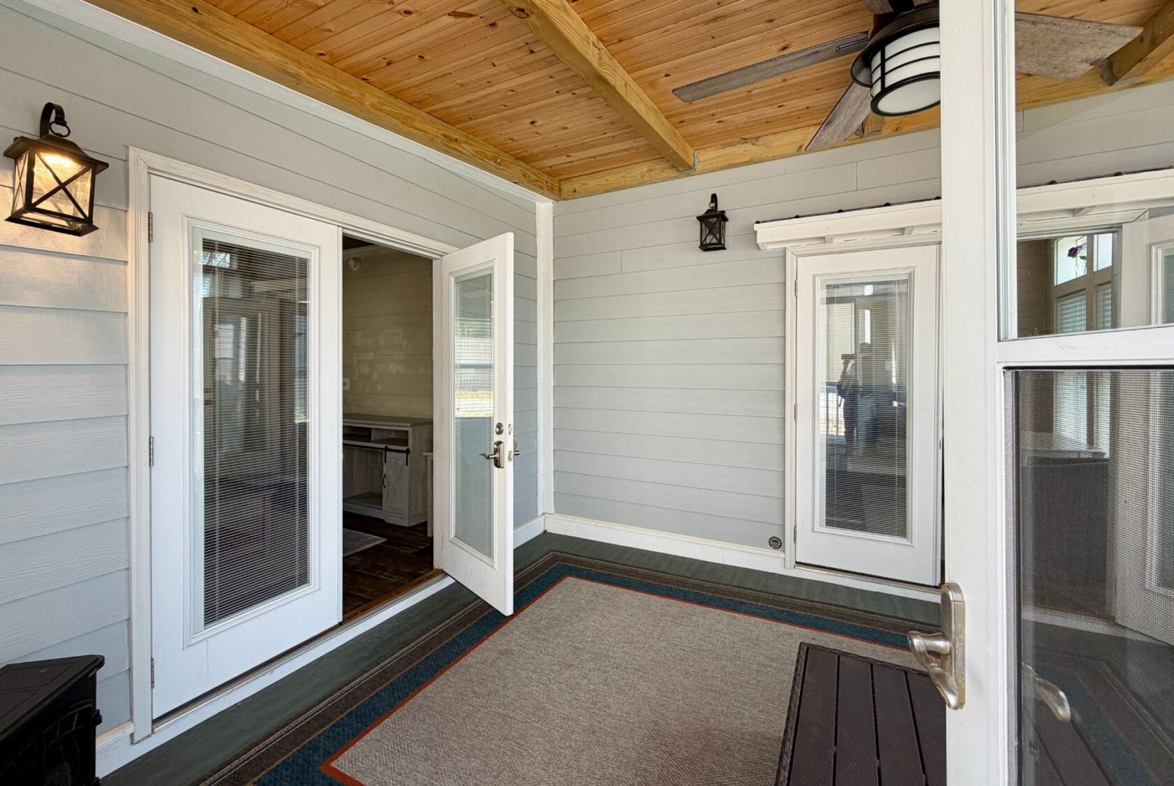 A bright sunroom with wood ceiling, gray walls, French doors, and a ceiling fan at 53 Highland Hill Lane.