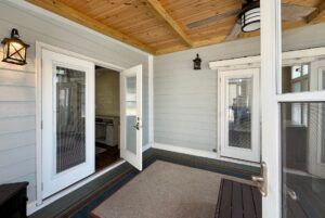 A bright sunroom with wood ceiling, gray walls, French doors, and a ceiling fan at 53 Highland Hill Lane.