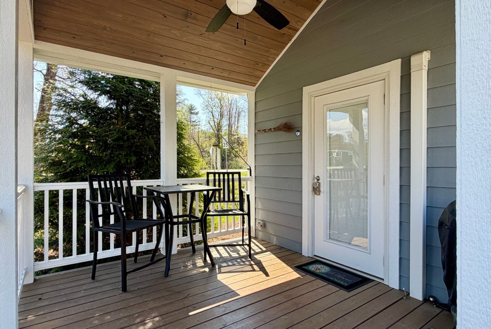 Charming small porch at 47 Drifting Brook, featuring a table, chairs, white railing, and a wooden ceiling fan.