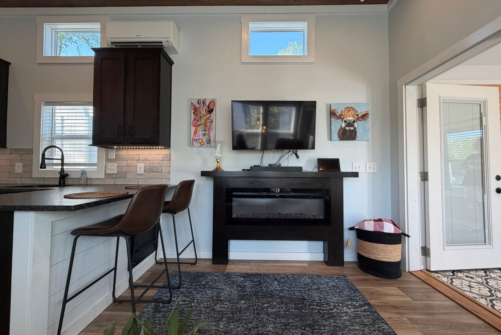 Living room at 106 Meandering Lane with TV above fireplace, counter seating, and animal art on the wall.