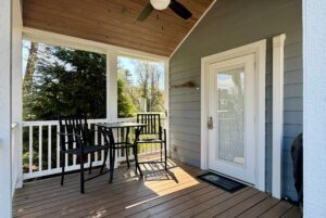 Charming small porch at 47 Drifting Brook, featuring a table, chairs, white railing, and a wooden ceiling fan.