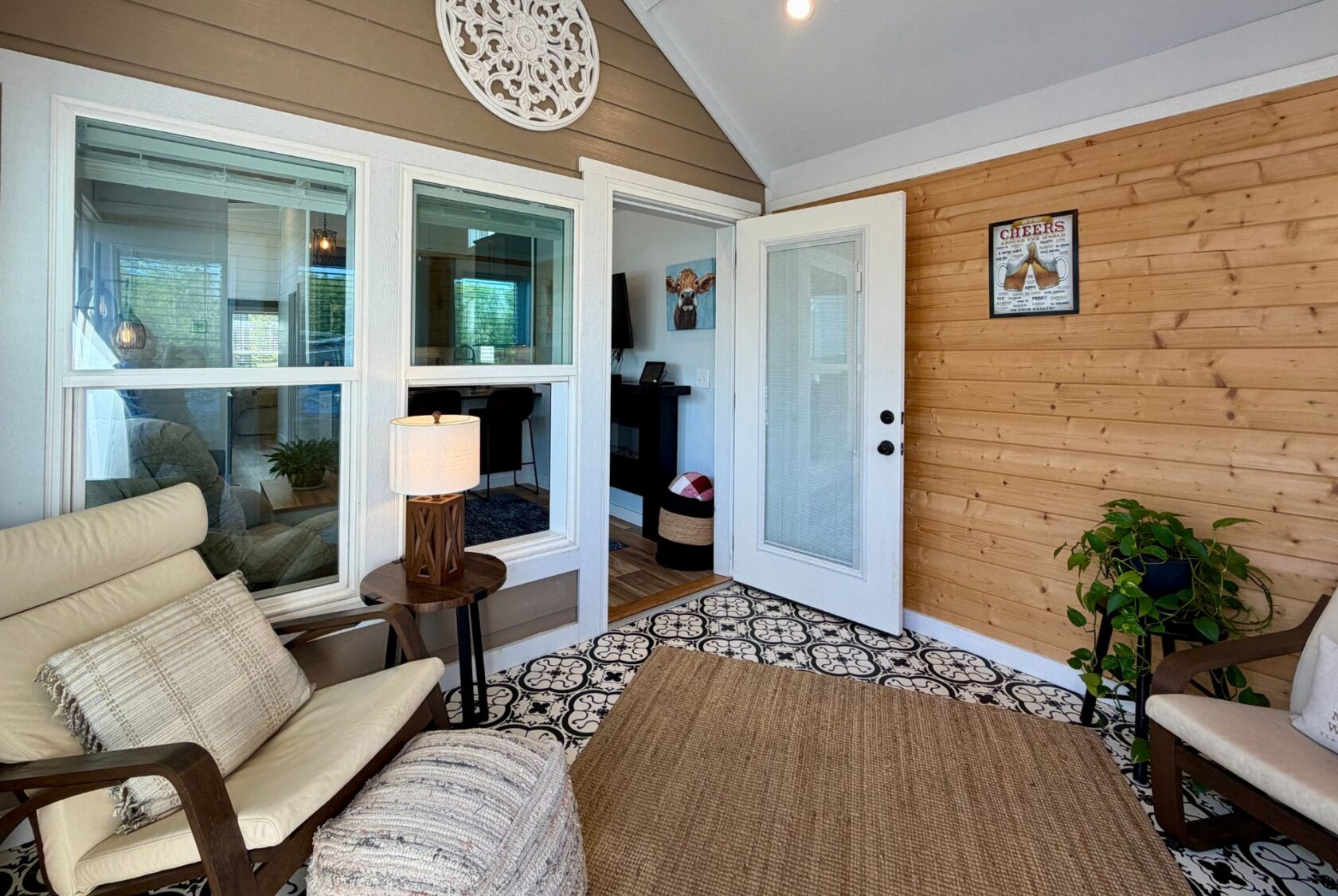 Bright sunroom at 106 Meandering Lane with cozy chairs, patterned floor, wood accent wall, and glass door to another room.