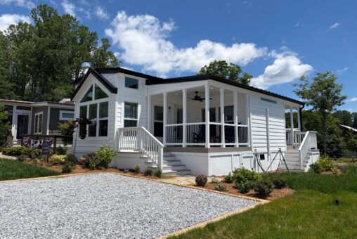 A small white house at 116 Meandering Lane with a screened porch, steps, and gravel driveway, surrounded by trees and green grass.