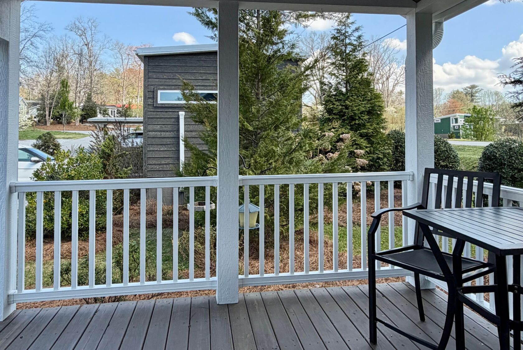 A porch at 47 Drifting Brook with a black table and chairs overlooks a garden and modern building in this real estate gem.