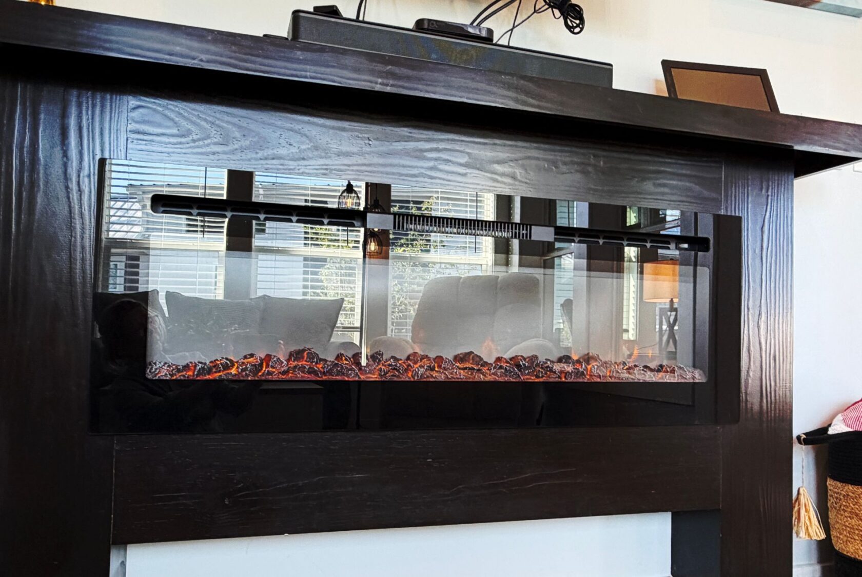 Modern electric fireplace with glowing embers on Meandering Lane, set in a dark wooden mantle for a cozy living room feel.