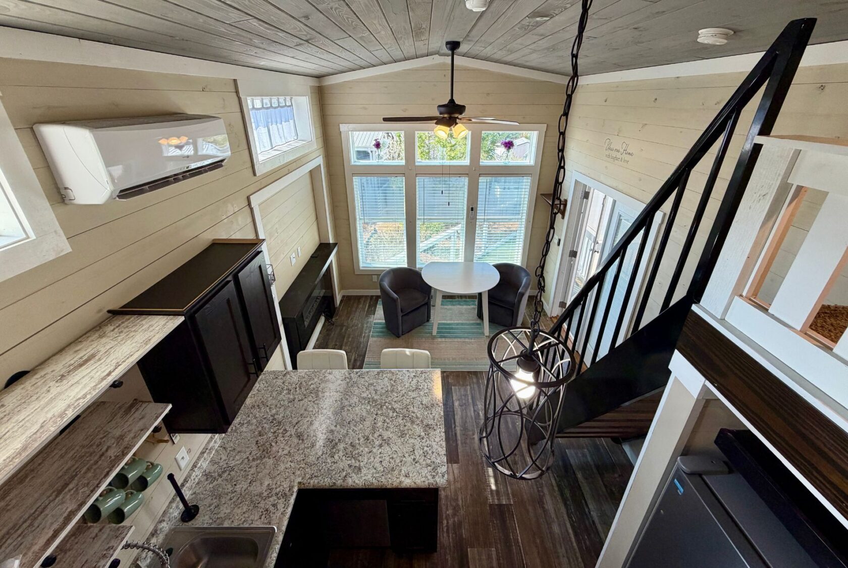 A modern tiny house interior at 53 Highland Hill Lane features a kitchen, dining area, and stairs to a loft.