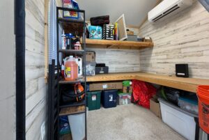A small organized storage room at 106 Meandering Lane with shelves, bins, boxes, and supplies neatly arranged.