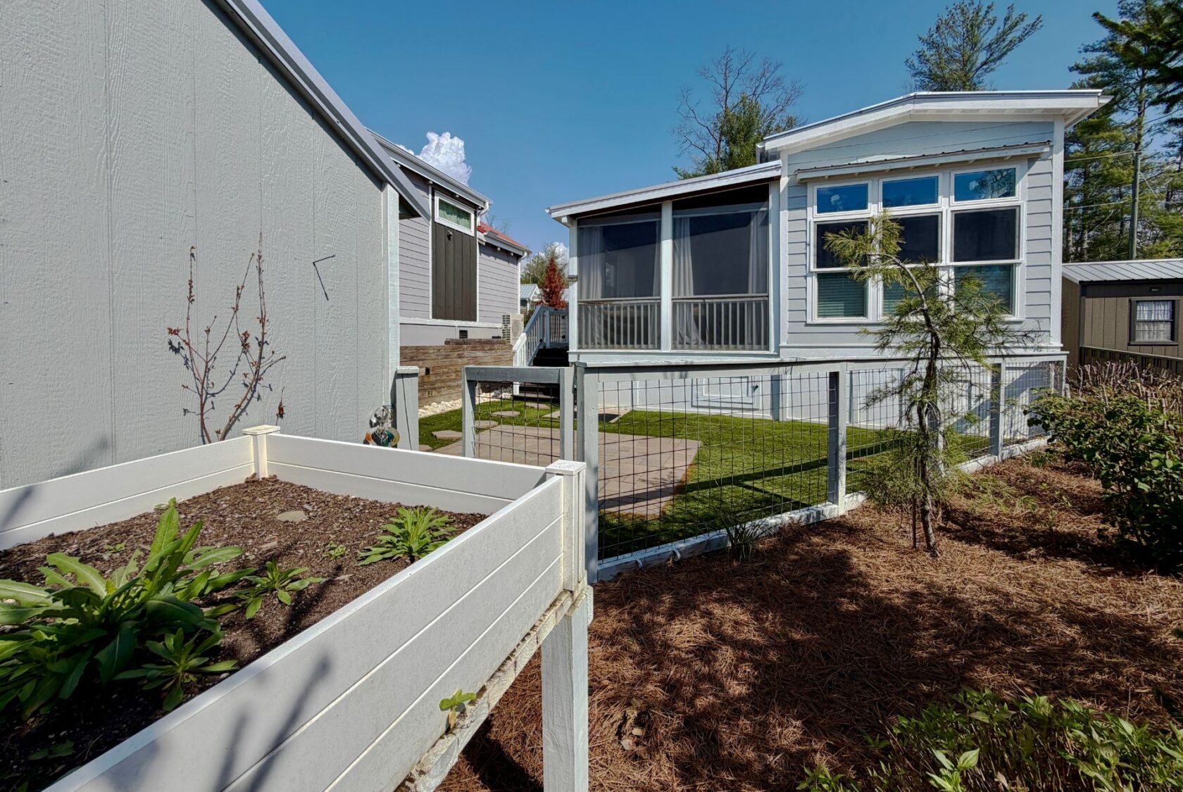 Small backyard on Highland Hill Lane with a raised garden bed, patio, and white house featuring a screened porch.