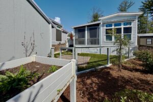 Small backyard on Highland Hill Lane with a raised garden bed, patio, and white house featuring a screened porch.