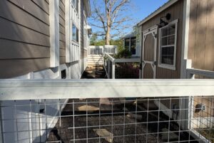 Narrow fenced pathway at 106 Meandering Lane with a stone path, leading to stairs and a wooden deck.
