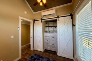 Small room at 53 Highland Hill Lane with barn doors open to reveal shelves, storage boxes, and drawers under a wall-mounted AC.