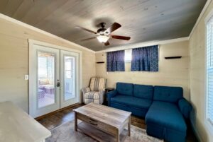 Cozy living room at 53 Highland Hill with blue sofa, striped armchair, wooden coffee table, and ceiling fan.