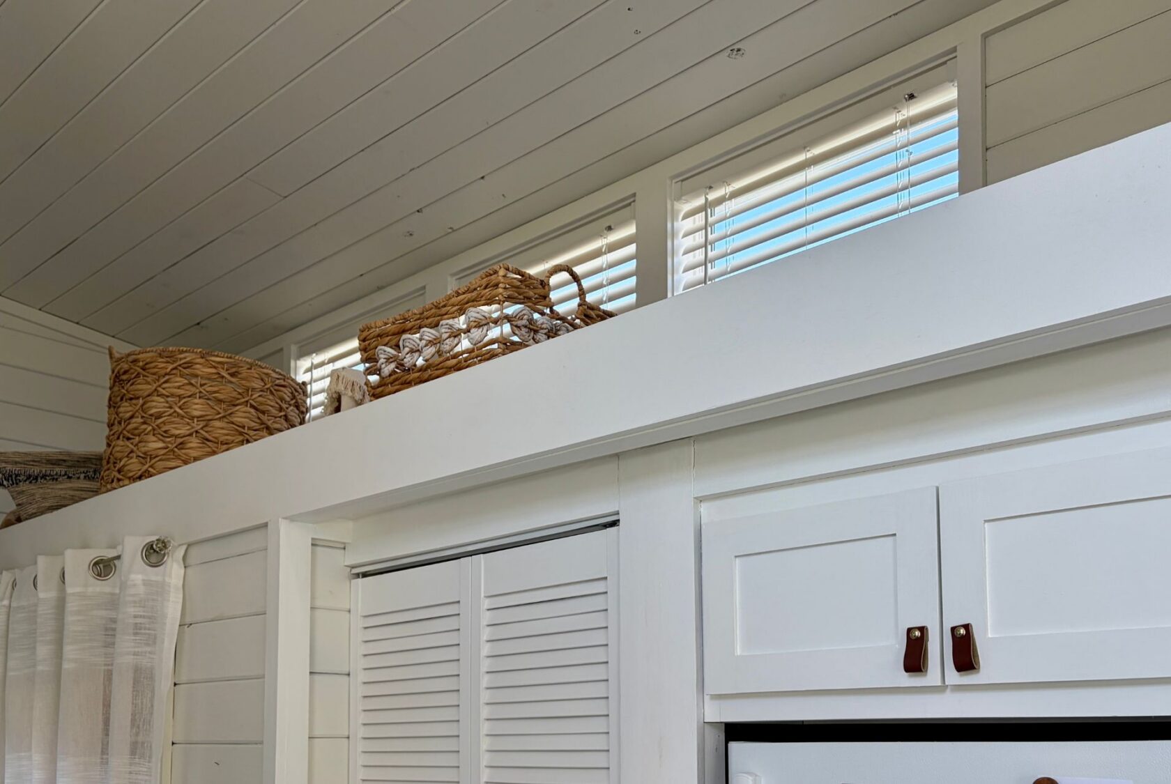 Wicker baskets on a high white shelf in the bright, modern real estate of 47 Drifting Brook Lane.