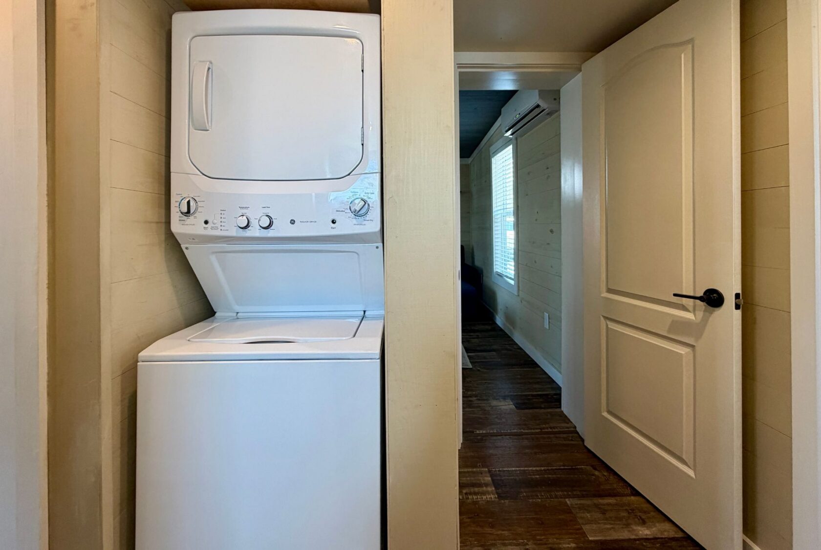 Stacked washer and dryer in a small laundry nook on Highland Hill Lane, next to an open door leading to a hallway.