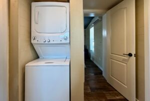 Stacked washer and dryer in a small laundry nook on Highland Hill Lane, next to an open door leading to a hallway.