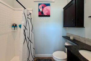 Bathroom at 106 Meandering Lane with a shower, black and white curtain, dark wood cabinets, and flamingo painting.