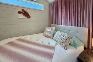 Cozy bedroom with floral pillows, a pink striped blanket, and mauve curtains at 47 Drifting Brook Lane.