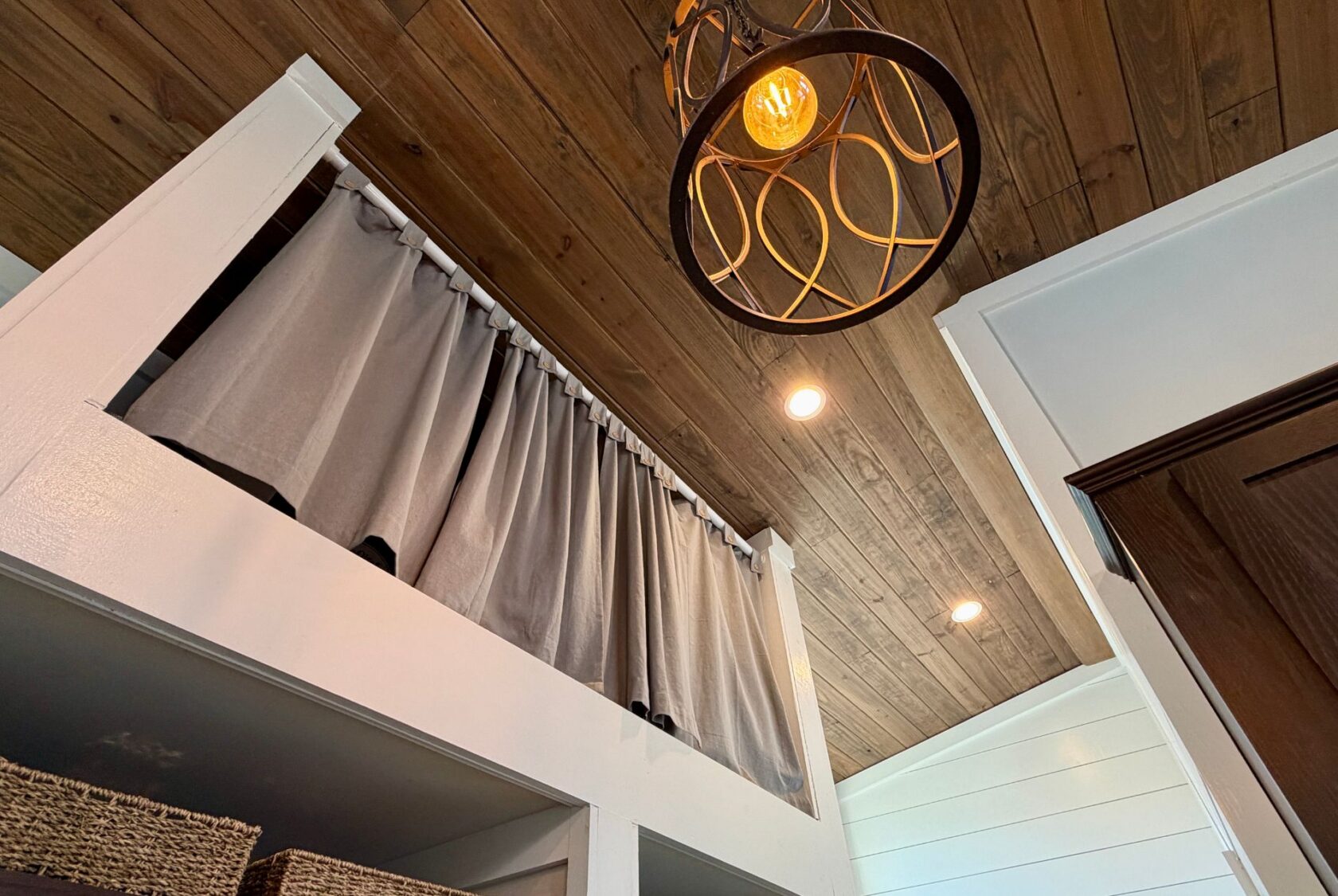 View of a loft at 106 Meandering Lane with closed gray curtains, wood ceiling, and modern recessed lighting.