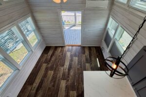 View from above of a bright room with wood floors, large windows, and open doors to Strolling Easy Lane.