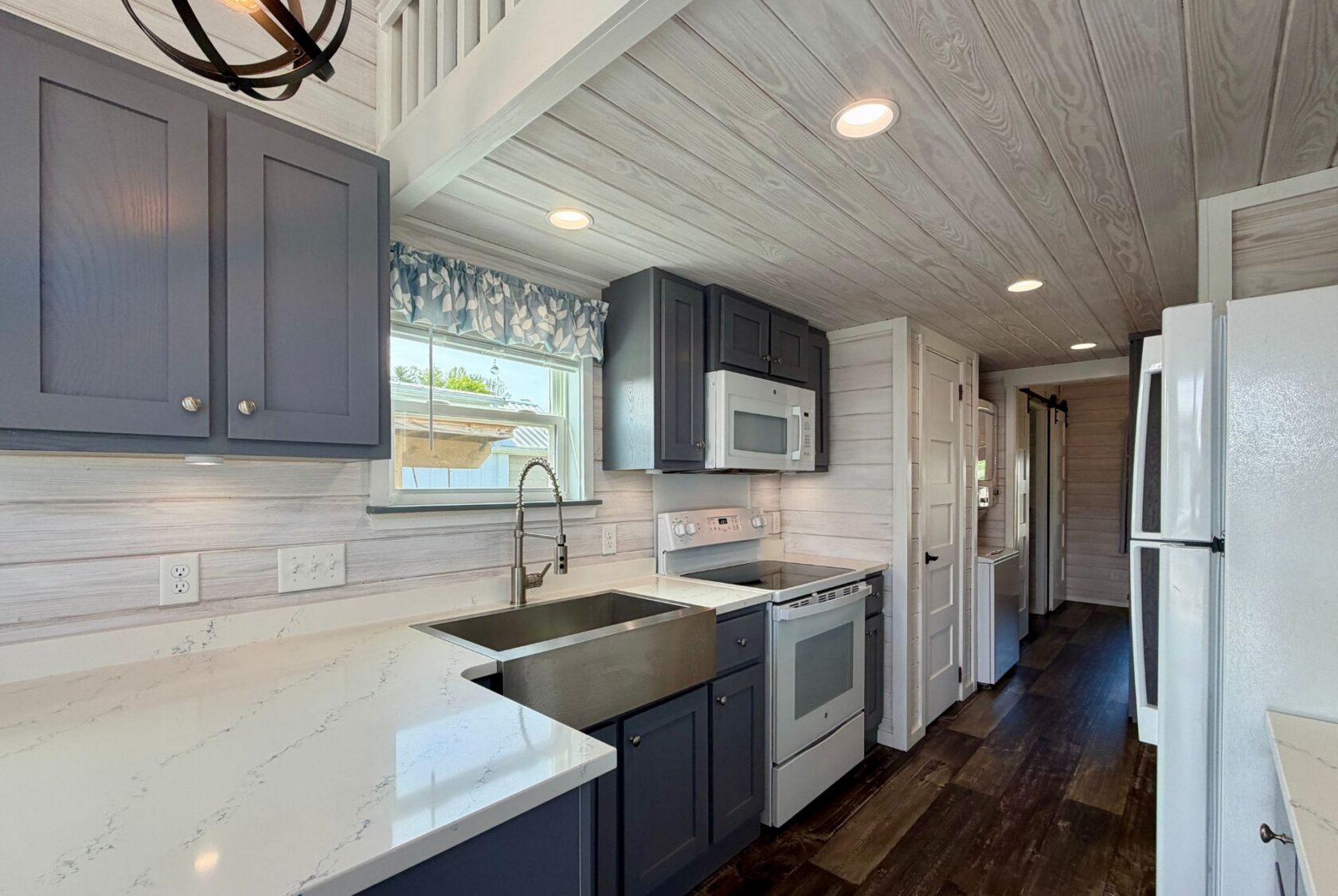 Modern kitchen with gray cabinets, marble countertops, and a Strolling Easy Lane vibe in wood-paneled walls and ceiling.