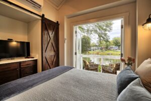 Cozy bedroom at 132 Drifting Brook with patio doors, lake views, and two chairs—an inviting real estate gem.