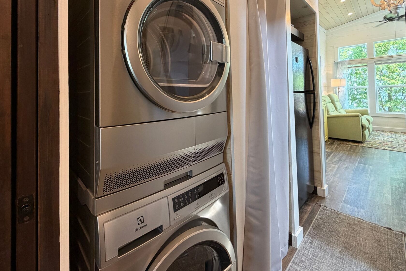 Stacked Electrolux washer and dryer at 59 Drifting Brook, next to a hallway leading to a bright living room.
