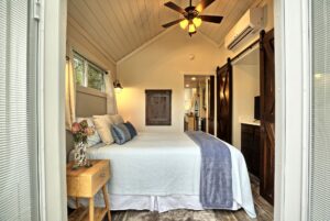 Cozy bedroom at 132 Drifting Brook with wood accents, barn doors, ceiling fan, and a nightstand with flowers.