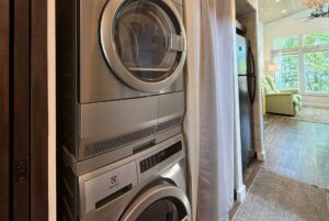 Stacked Electrolux washer and dryer at 59 Drifting Brook, next to a hallway leading to a bright living room.