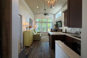 Bright living room at 59 Drifting Brook Lane with large windows, cozy seating, and a kitchen with dark wood cabinets.