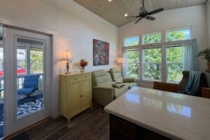 Bright living room at 59 Drifting Brook with large windows, two recliners, a yellow sideboard, and sunroom porch view.