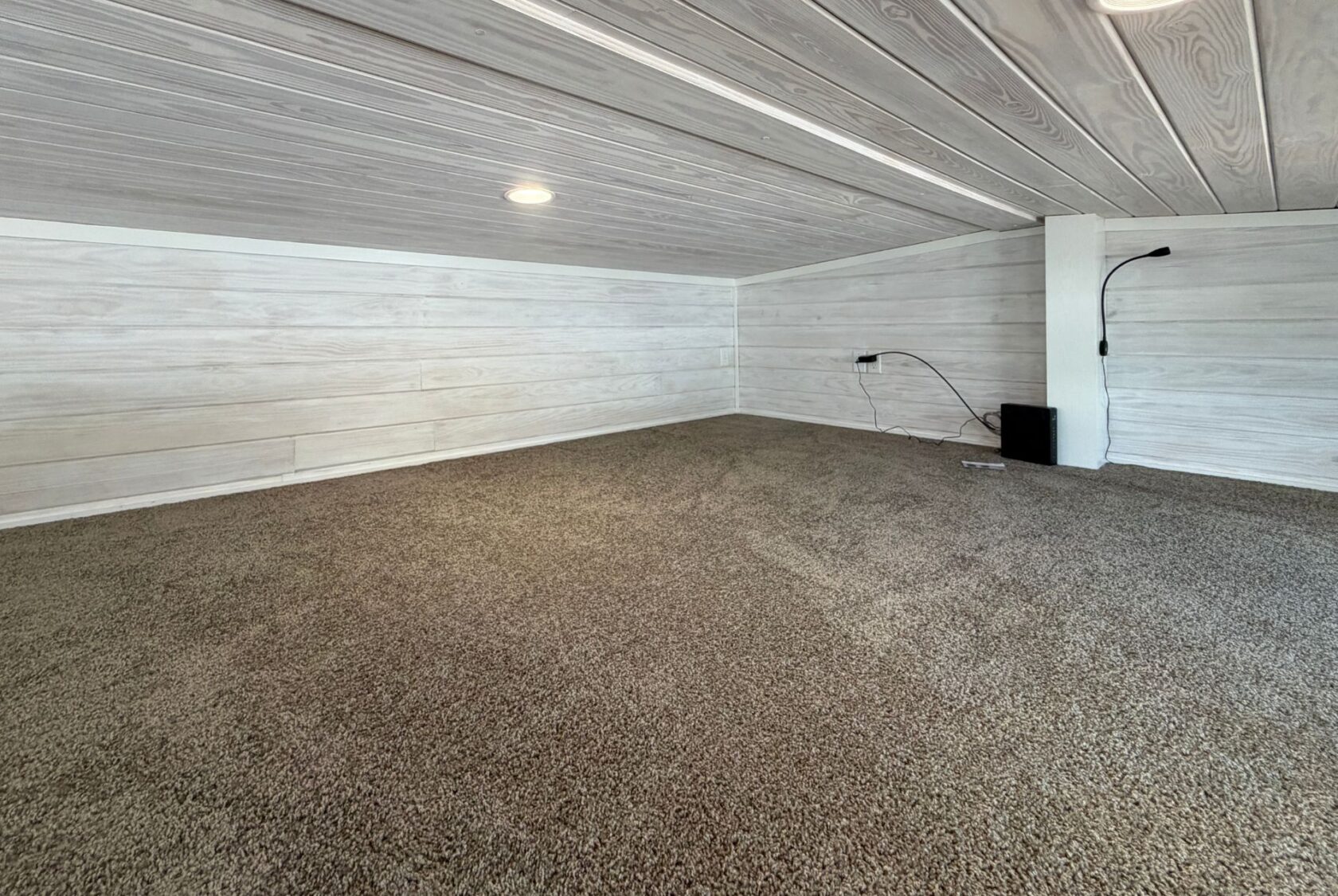 Cozy low-ceiling room on 15 Easy Lane with carpeted floor, white wooden walls, and recessed lighting.